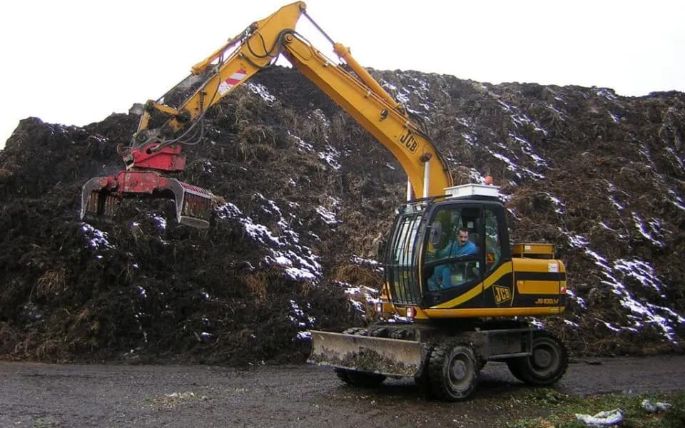Mobiele kraan met grijper op een berg bouw- en sloopafval